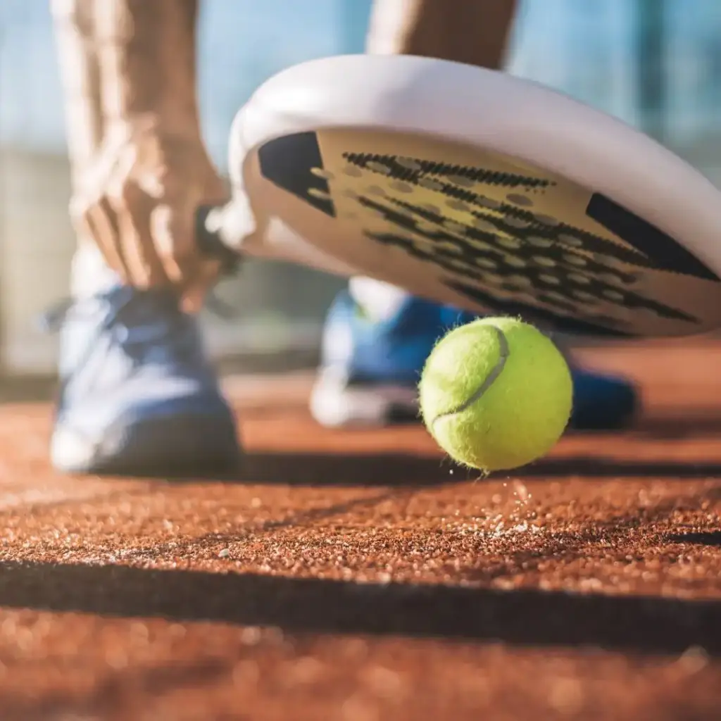 mand slår til padel bold med et hvidt og blåt padel bat - bedste padel bolde